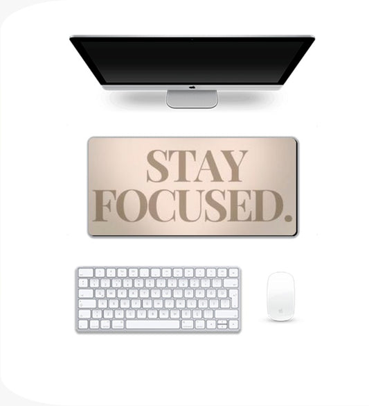 Computer setup with a desk pad that says 'Stay Focused' Gaming Pad